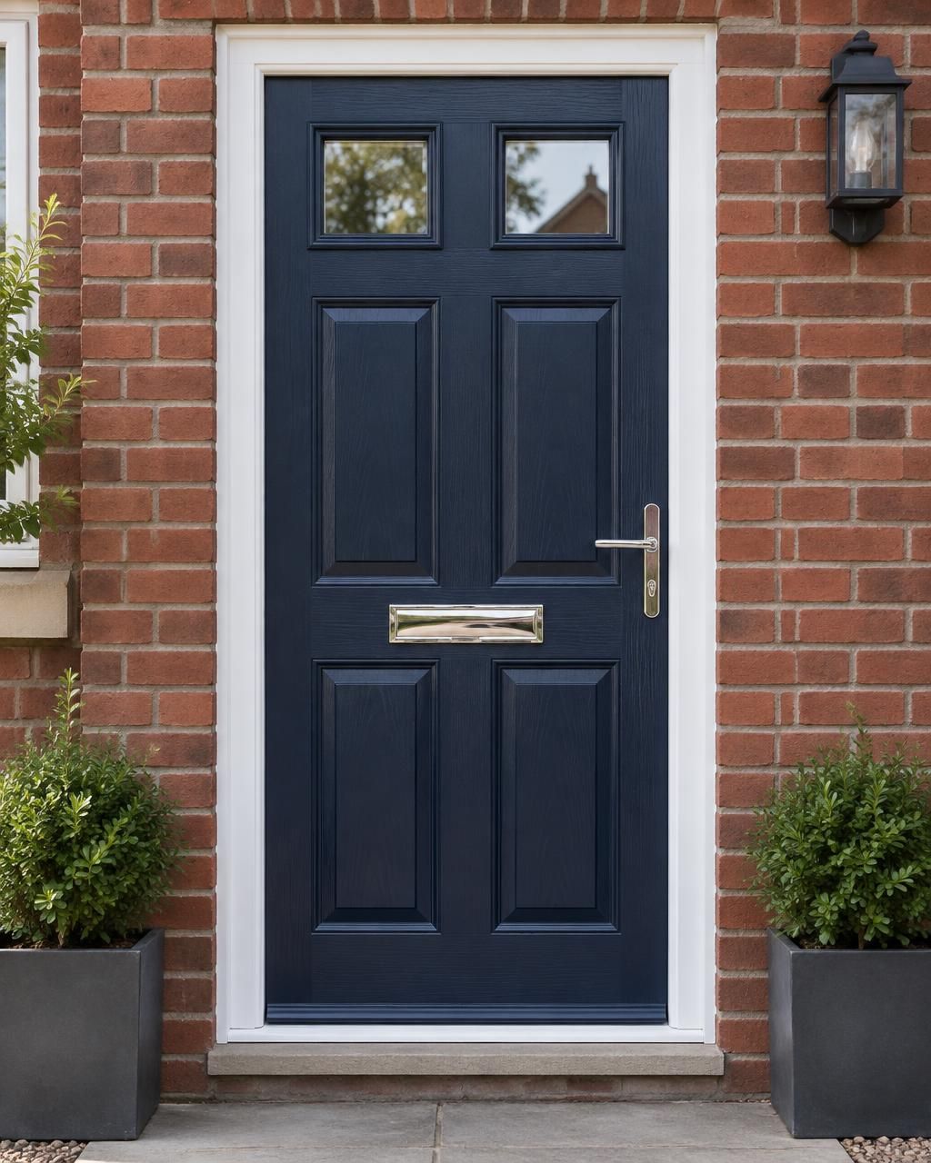 Navy blue six-panel composite front door with two small glazed top panels, chrome furniture and a white surround on a red-brick home